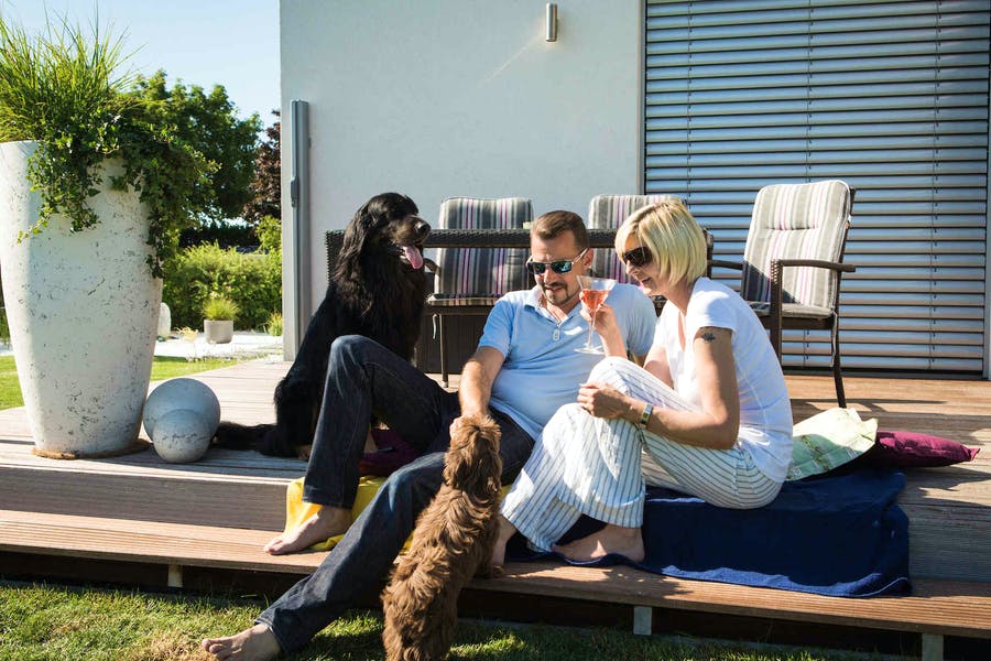 Paar sitzt mit seinen beiden Hunden vor ihrem neuen VARIO-HAUS